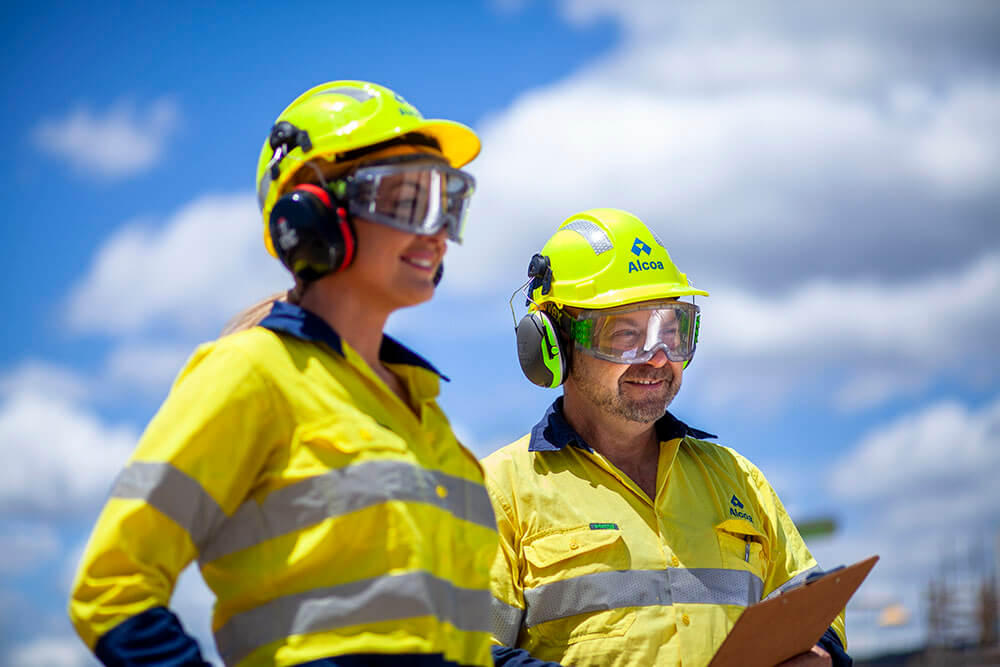 Two individuals in high visibility clothing with a clip board